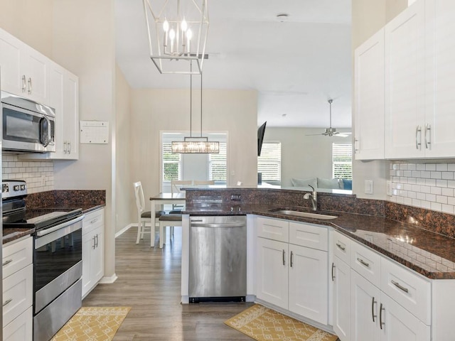 kitchen with pendant lighting, sink, appliances with stainless steel finishes, white cabinets, and dark stone counters