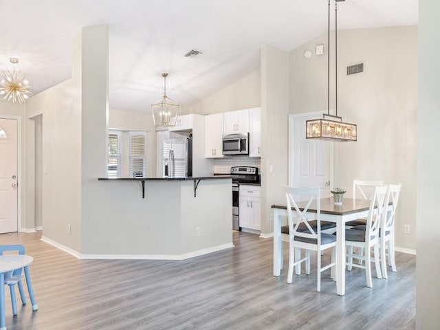 kitchen with pendant lighting, a notable chandelier, white cabinets, and appliances with stainless steel finishes