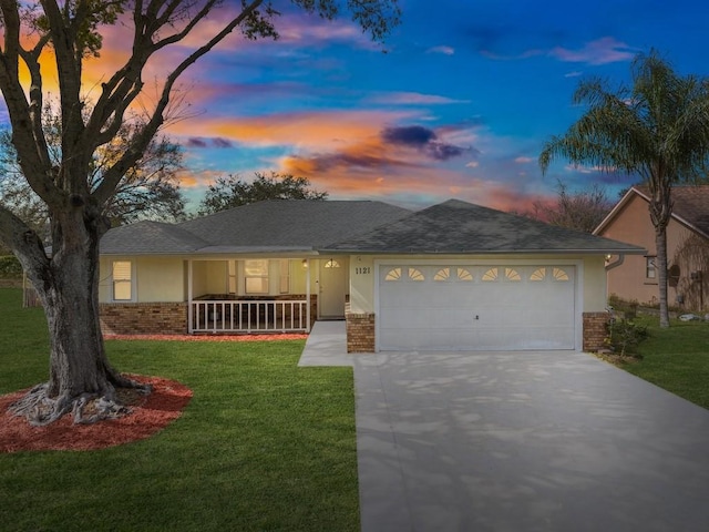 ranch-style home with a garage, a porch, and a yard