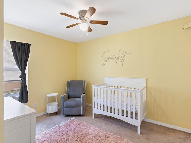 unfurnished bedroom with a nursery area, light colored carpet, and ceiling fan