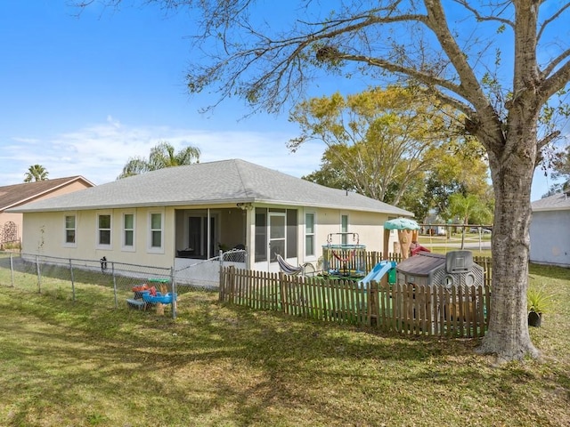 back of house featuring a lawn, a sunroom, and a playground