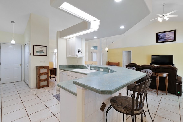 kitchen featuring sink, a kitchen bar, white cabinets, pendant lighting, and vaulted ceiling