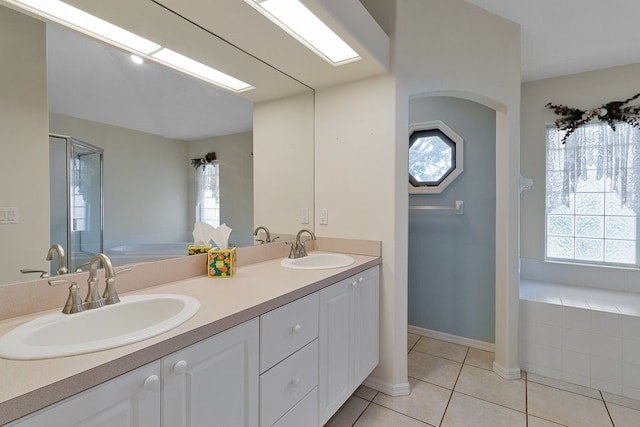 bathroom featuring tile patterned flooring, vanity, and a relaxing tiled tub