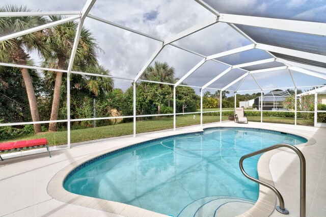 view of pool with glass enclosure and a patio area