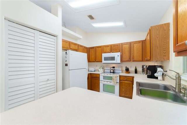 kitchen featuring light countertops, vaulted ceiling, white appliances, a sink, and visible vents
