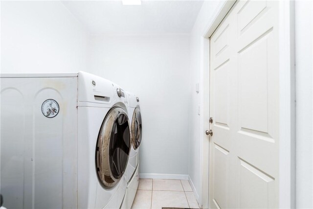 clothes washing area with washing machine and clothes dryer, baseboards, laundry area, and light tile patterned floors