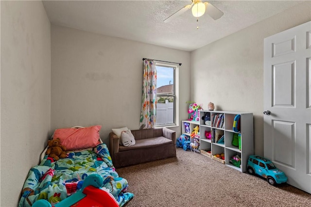 playroom featuring ceiling fan, carpet floors, and a textured ceiling