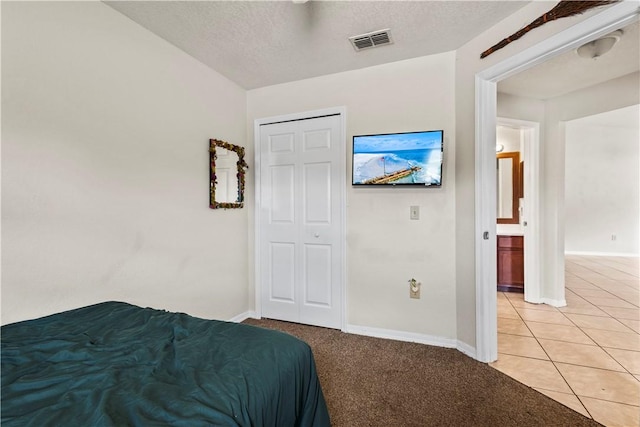 tiled bedroom with a closet and a textured ceiling