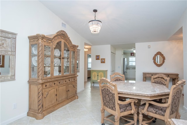 dining area featuring light tile patterned floors, an inviting chandelier, and lofted ceiling