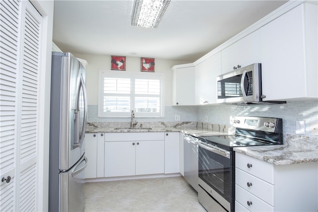 kitchen with backsplash, white cabinets, sink, light stone countertops, and stainless steel appliances