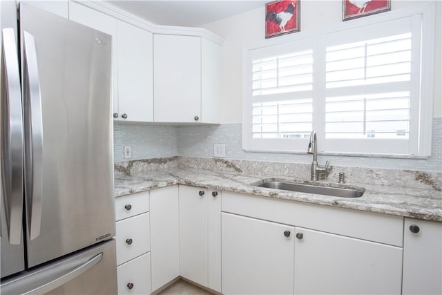 kitchen featuring white cabinets, stainless steel fridge, a wealth of natural light, and sink