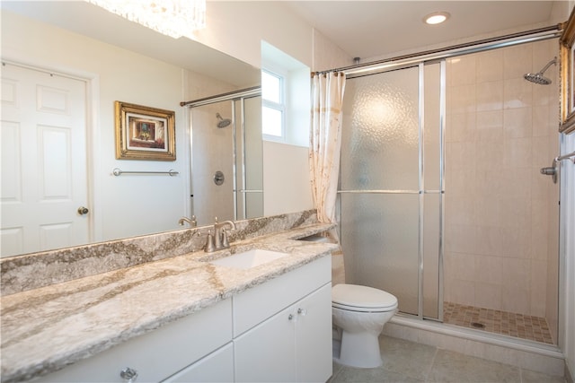 bathroom with tile patterned floors, a shower with door, vanity, and toilet