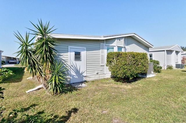 view of side of home featuring a lawn and cooling unit