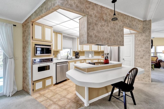 kitchen featuring appliances with stainless steel finishes, a kitchen breakfast bar, ornamental molding, sink, and pendant lighting