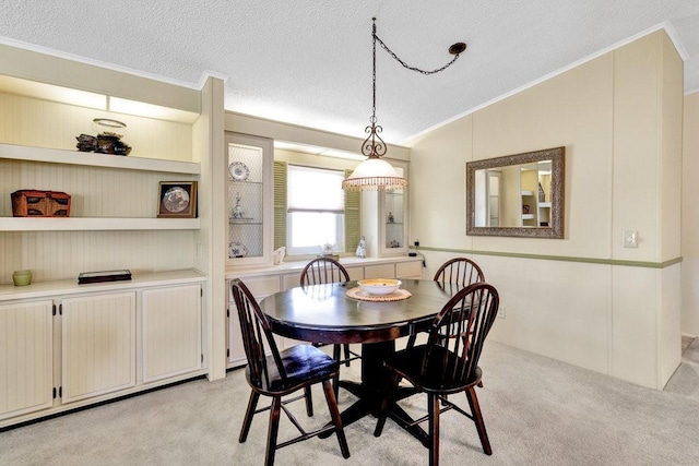 carpeted dining room featuring a textured ceiling, crown molding, and vaulted ceiling