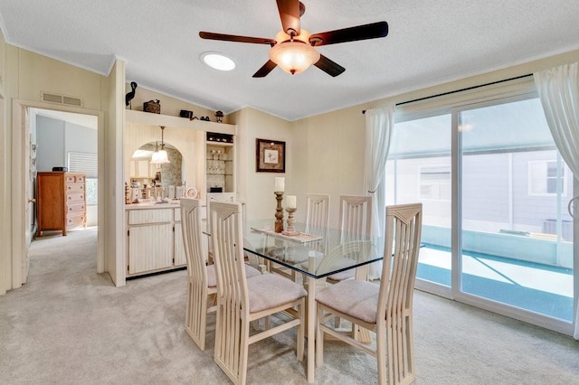 dining space featuring light carpet, a textured ceiling, vaulted ceiling, and ceiling fan