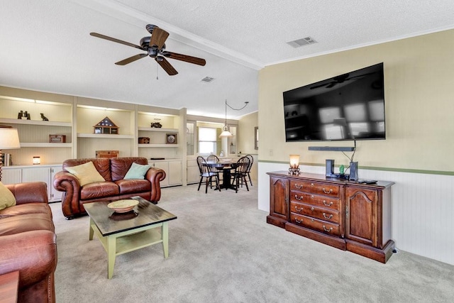 carpeted living room with a textured ceiling, ceiling fan, beam ceiling, and crown molding