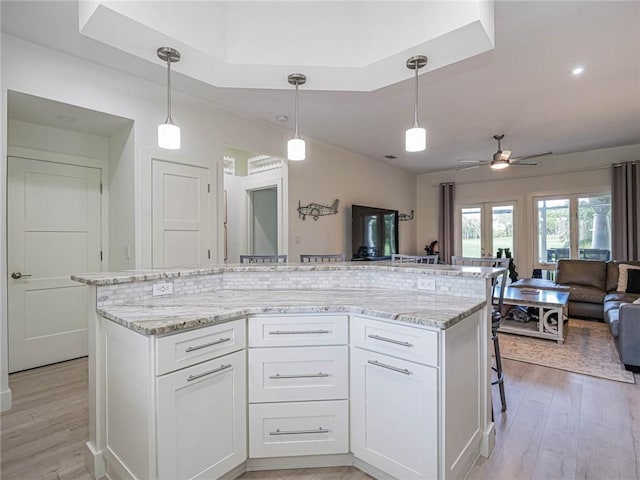 kitchen featuring white cabinetry, hanging light fixtures, a kitchen island, and light wood-type flooring