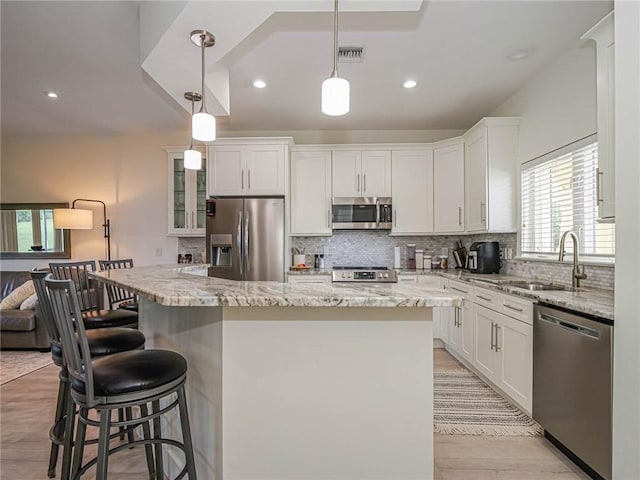 kitchen featuring white cabinetry, sink, stainless steel appliances, and a kitchen island