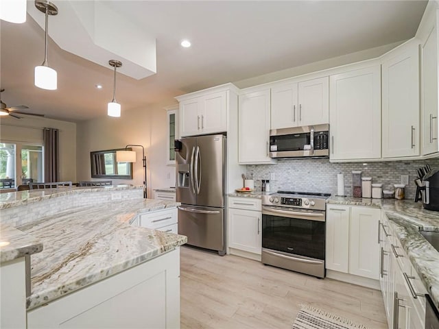 kitchen featuring decorative light fixtures, white cabinetry, backsplash, stainless steel appliances, and light stone countertops