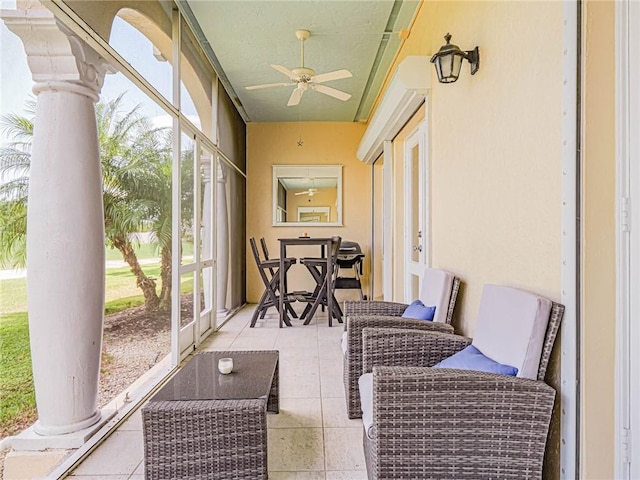 sunroom with decorative columns and ceiling fan