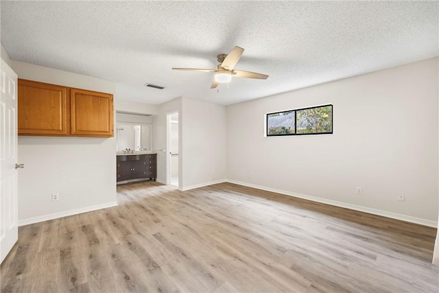 2821 21st Pl, Vero Beach, FL 32960 - unfurnished living room with ceiling fan, light wood-type flooring, baseboards, a textured ceiling, and a sink