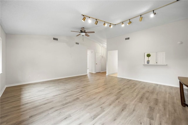 2821 21st Pl, Vero Beach, FL 32960 - unfurnished living room with ceiling fan, light wood-style flooring, baseboards, vaulted ceiling, and rail lighting