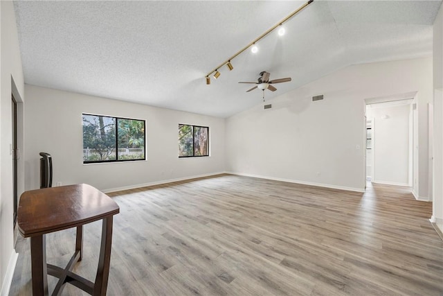 2821 21st Pl, Vero Beach, FL 32960 - unfurnished living room featuring light wood-style floors, ceiling fan, baseboards, lofted ceiling, and a textured ceiling
