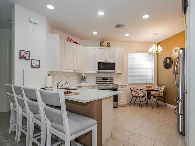 kitchen featuring pendant lighting, white cabinetry, a breakfast bar area, kitchen peninsula, and stainless steel appliances