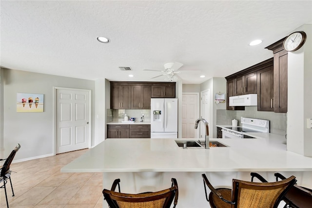 kitchen featuring ceiling fan, sink, kitchen peninsula, white appliances, and decorative backsplash