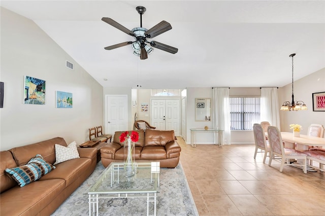 tiled living room with ceiling fan with notable chandelier and vaulted ceiling