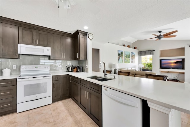 kitchen with kitchen peninsula, a textured ceiling, white appliances, vaulted ceiling, and sink