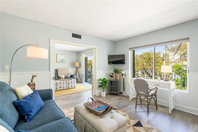 living room featuring a wainscoted wall, wood finished floors, and visible vents