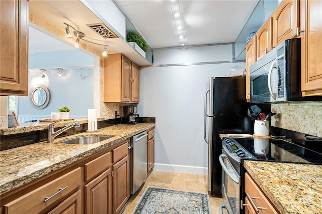 kitchen with light stone counters, stainless steel appliances, tasteful backsplash, visible vents, and a sink