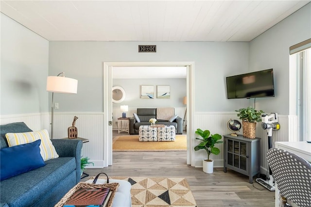 living area featuring wainscoting, wood finished floors, and visible vents