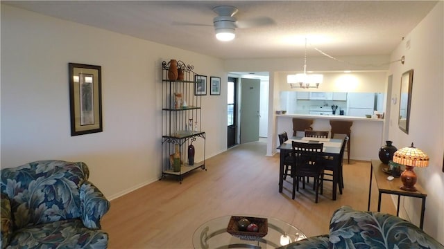 dining space featuring ceiling fan with notable chandelier, light hardwood / wood-style floors, and a textured ceiling