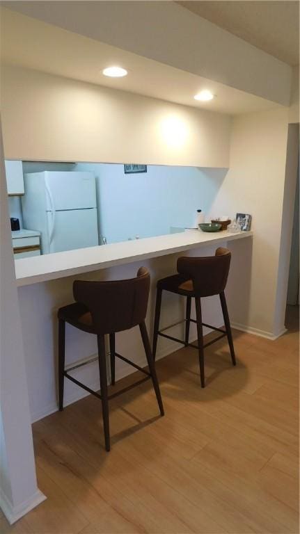 bar featuring white refrigerator and light hardwood / wood-style floors