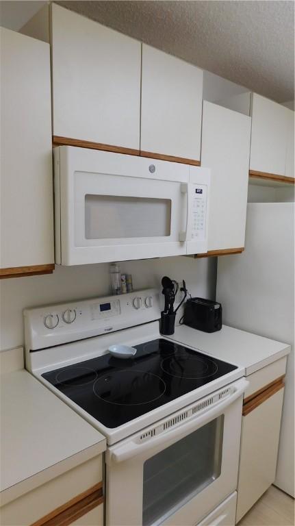 kitchen featuring white cabinets and white appliances