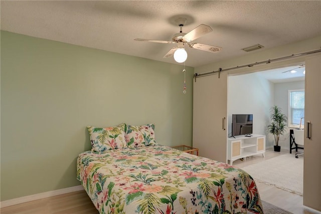 8520 US Highway 1 Unit 11E, Micco, FL 32976 - bedroom with a textured ceiling, a ceiling fan, visible vents, a barn door, and wood finished floors