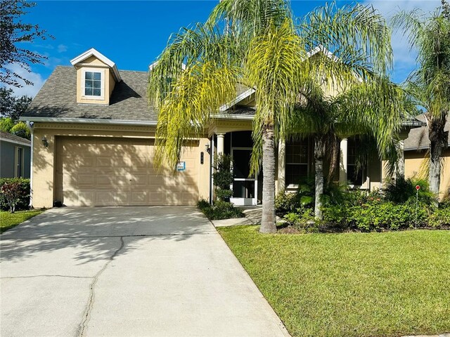 504 Sebastian Crossings Blvd, Sebastian, FL 32958 - view of front facade with a garage, driveway, a front lawn, a shingled roof, and stucco siding