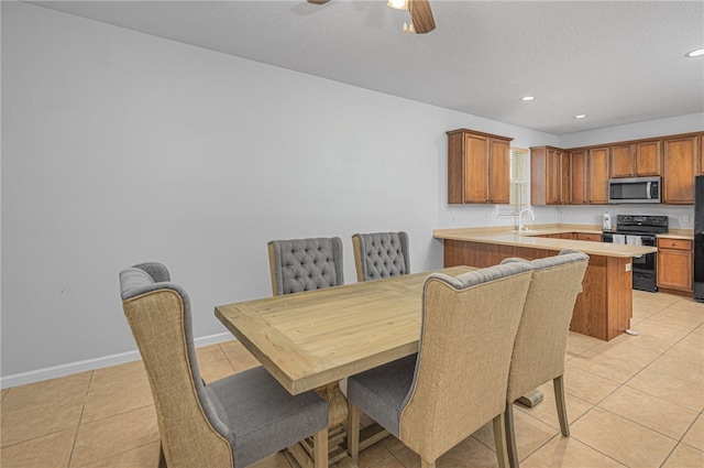 tiled dining room with ceiling fan and sink