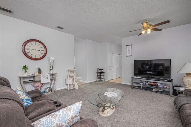 living room featuring ceiling fan, light carpet, and a textured ceiling