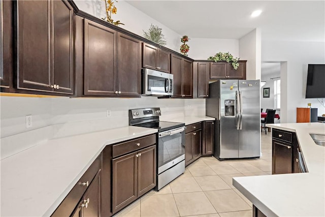 kitchen with dark brown cabinets, light tile patterned floors, and appliances with stainless steel finishes