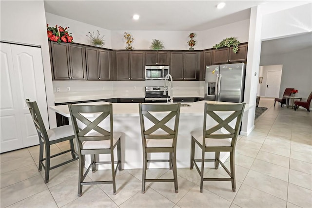 kitchen featuring a breakfast bar, sink, dark brown cabinetry, and stainless steel appliances