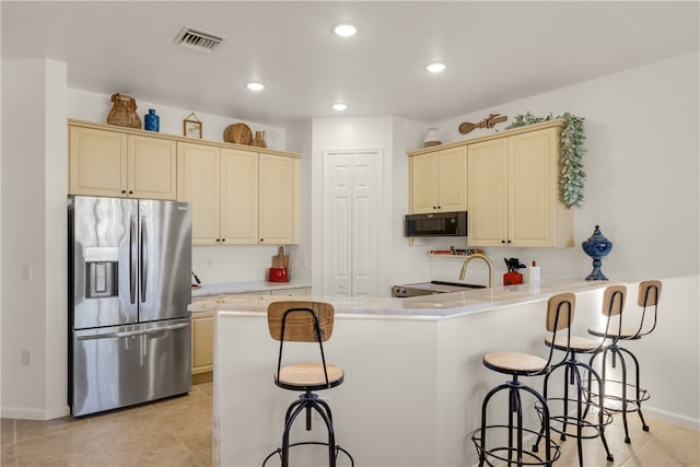 kitchen featuring kitchen peninsula, stainless steel refrigerator with ice dispenser, cream cabinets, and a breakfast bar area