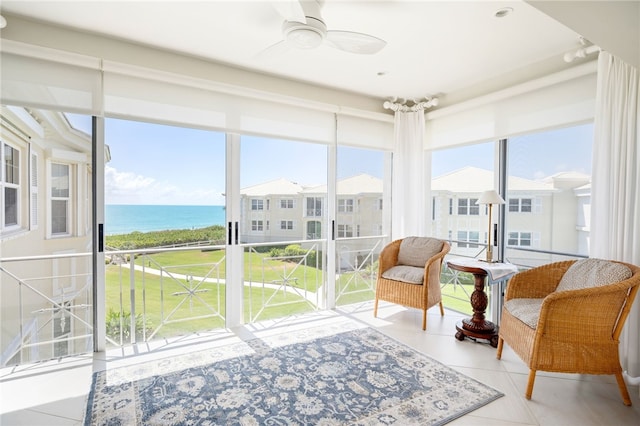 sunroom / solarium featuring ceiling fan and a water view