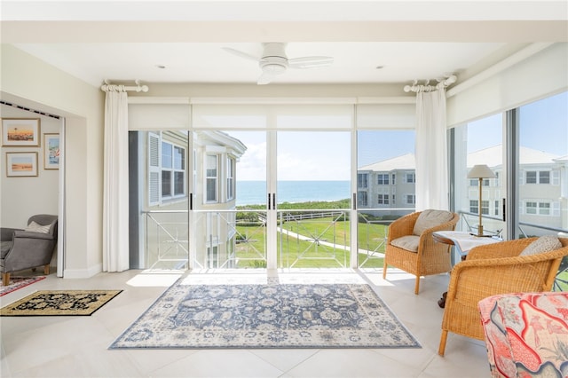 sunroom with ceiling fan and a water view