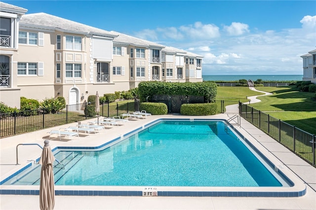 view of swimming pool featuring a lawn, a patio area, and a water view