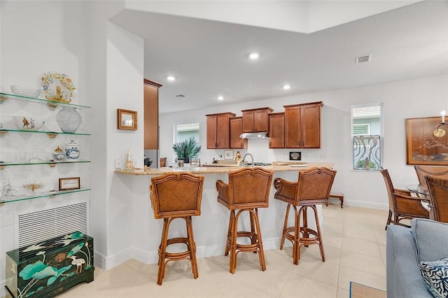 kitchen featuring kitchen peninsula, sink, a breakfast bar area, and a wealth of natural light