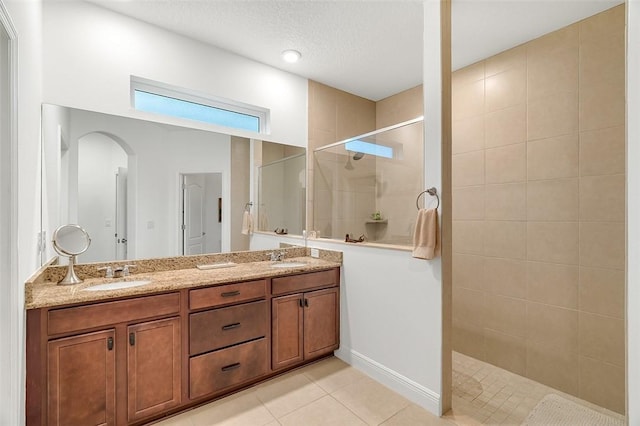 bathroom featuring vanity, a tile shower, tile patterned floors, and a textured ceiling